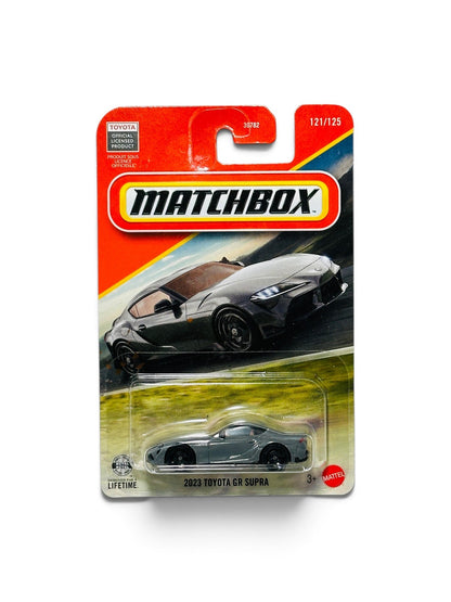 Matchbox packaged die-cast toy car featuring a dark gray 2023 Toyota GR Supra on a red and yellow card.